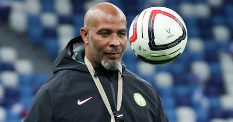 The coach watching a ball in the air at an empty stadium, training-ground scene