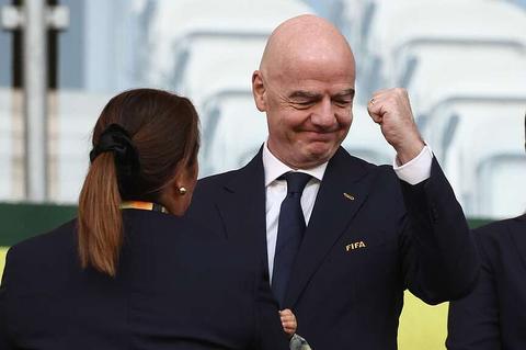 bald man in a suit smiling and gesturing with a woman