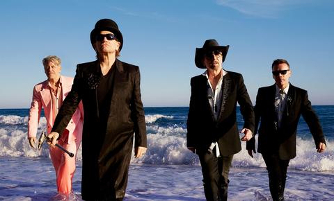 four men in suits on a beach