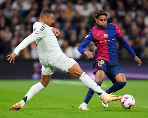 Real Madrid forward in white kit challenged by Barcelona No 19 in blue-and-red kit, ball at feet; shirt sponsors are par