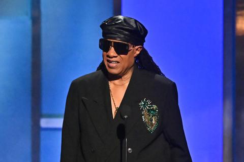 man in black beret and sunglasses speaking at a microphone
