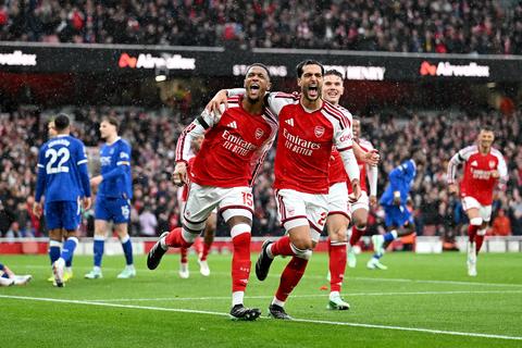 wide view of two Arsenal players celebrating in front of the crowd, Everton players in blue behind