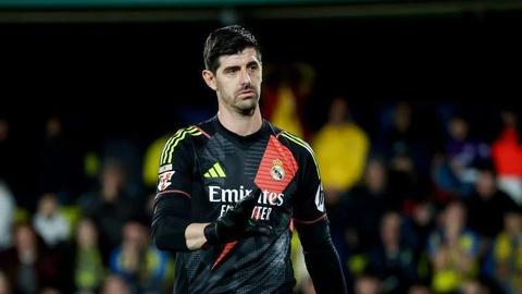 Same goalkeeper in dark Real Madrid kit with gloves, crowd behind