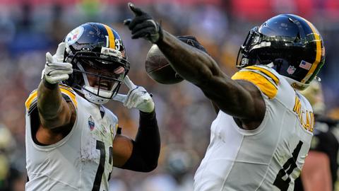 Two Steelers players in white kit celebrating, one holding the football and pointing upward