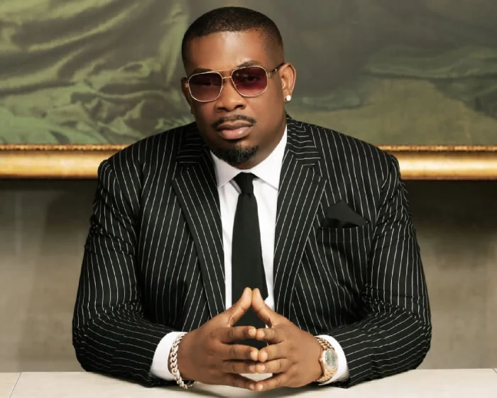 Don Jazzy in a pinstripe suit, hands clasped