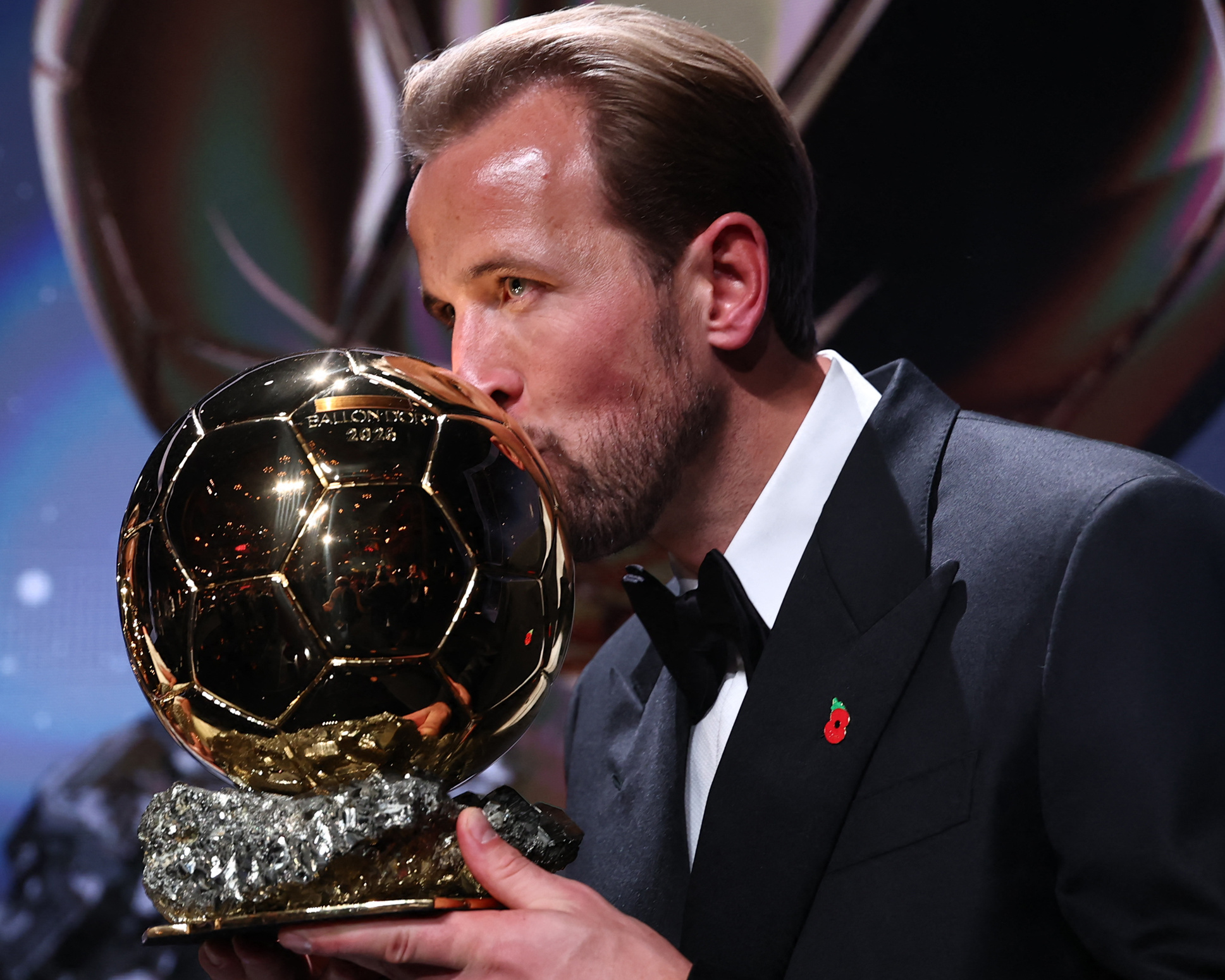 Harry Kane in a tuxedo kissing the Ballon d'Or trophy — the award moment of the story