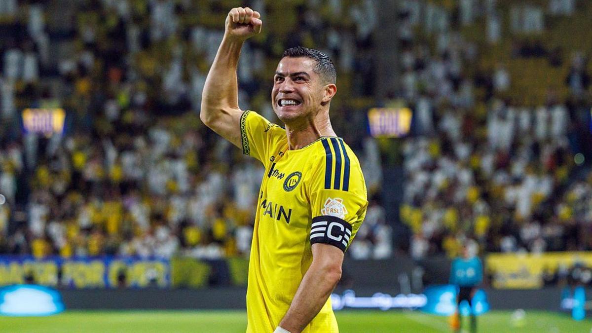 Cristiano Ronaldo in Al-Nassr yellow kit, fist raised, celebrating in front of a packed stand