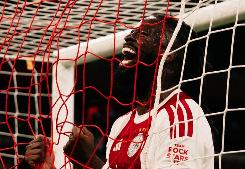 player celebrating with a shout behind the goal net, Ajax shirt with 'Team Rock Stars' sleeve text