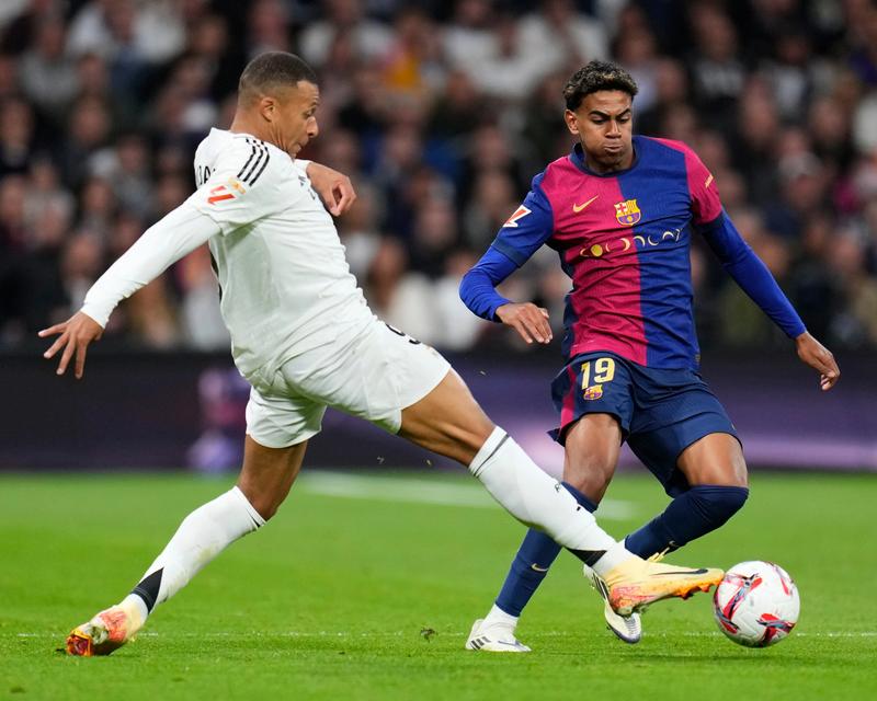 Real Madrid forward in white kit challenged by Barcelona No 19 in blue-and-red kit, ball at feet; shirt sponsors are par
