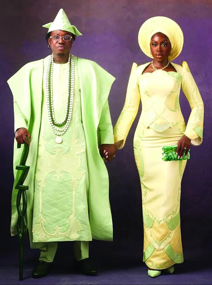 full-length studio shot of groom and bride in pale green aso-oke holding hands