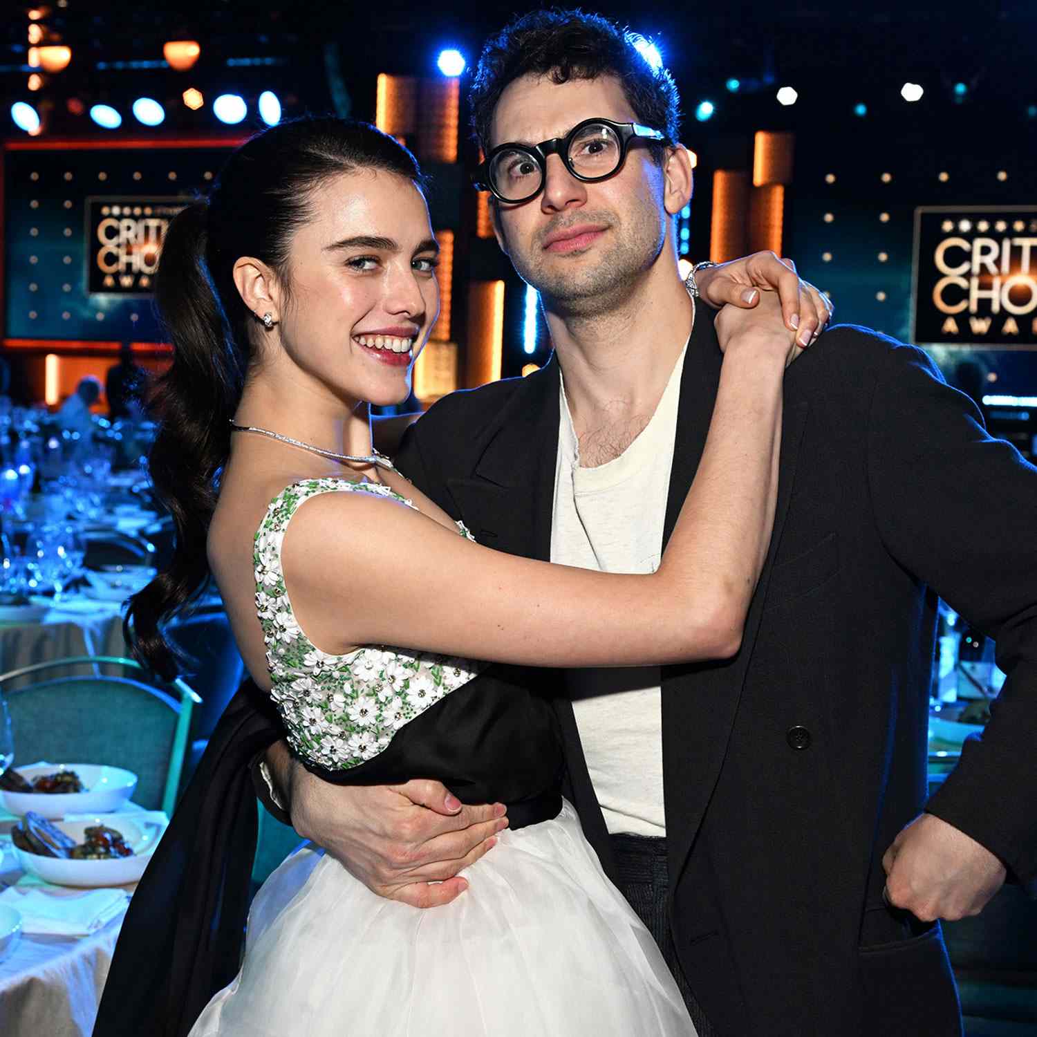 Jack Antonoff and Margaret Qualley embracing at the Critics Choice Awards, award signage in the background