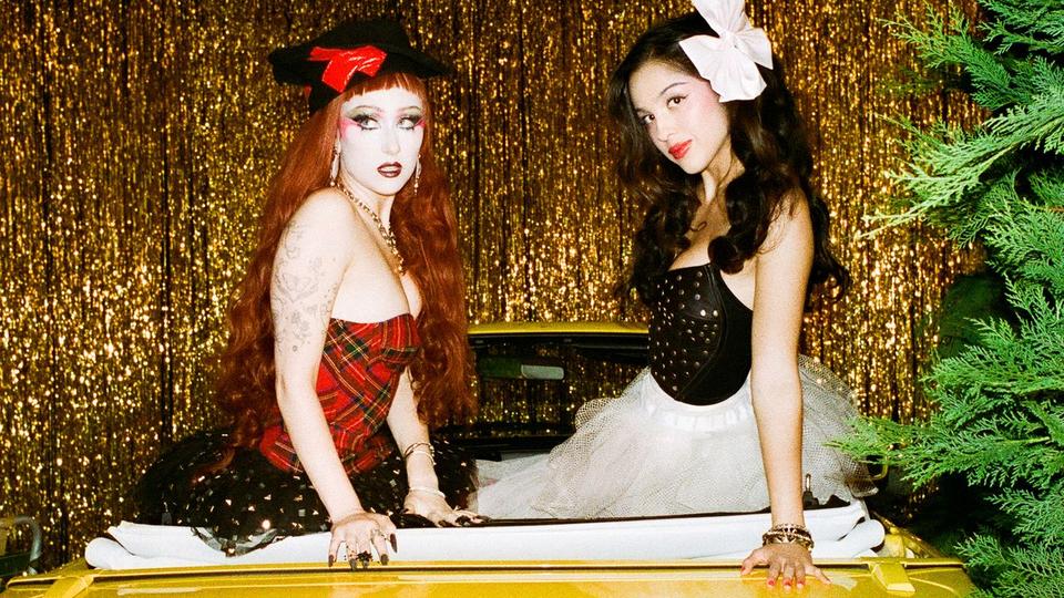 two women posing against a gold curtain
