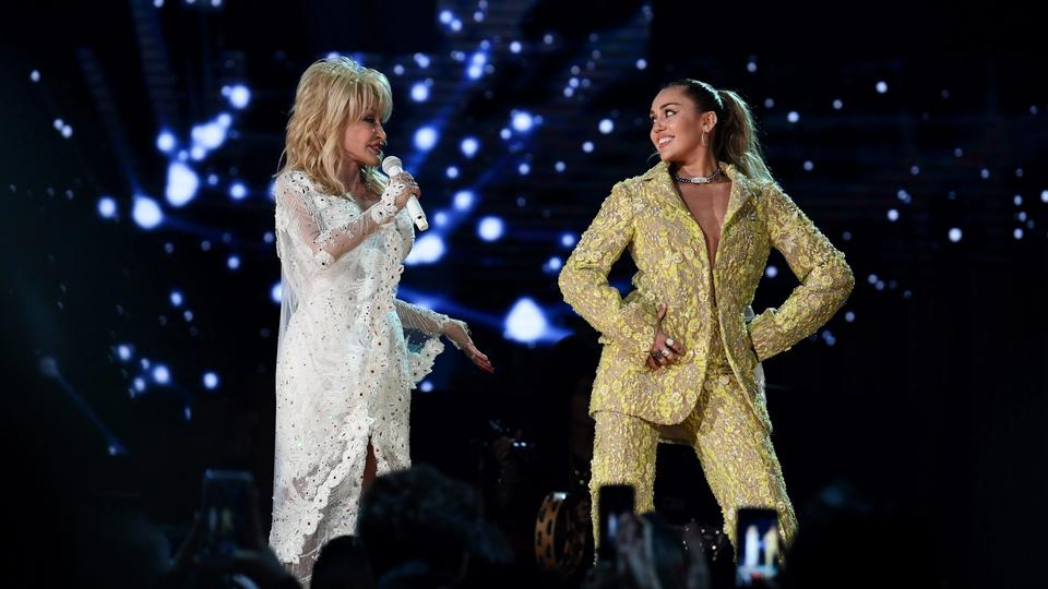 two women singing on a stage with blue lights in the background