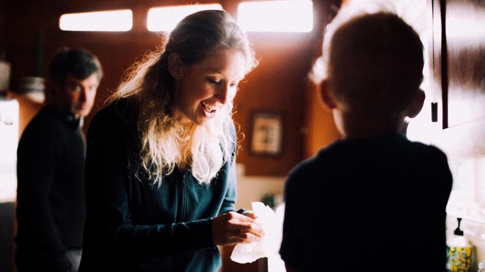 a woman smiling in a room with two other people