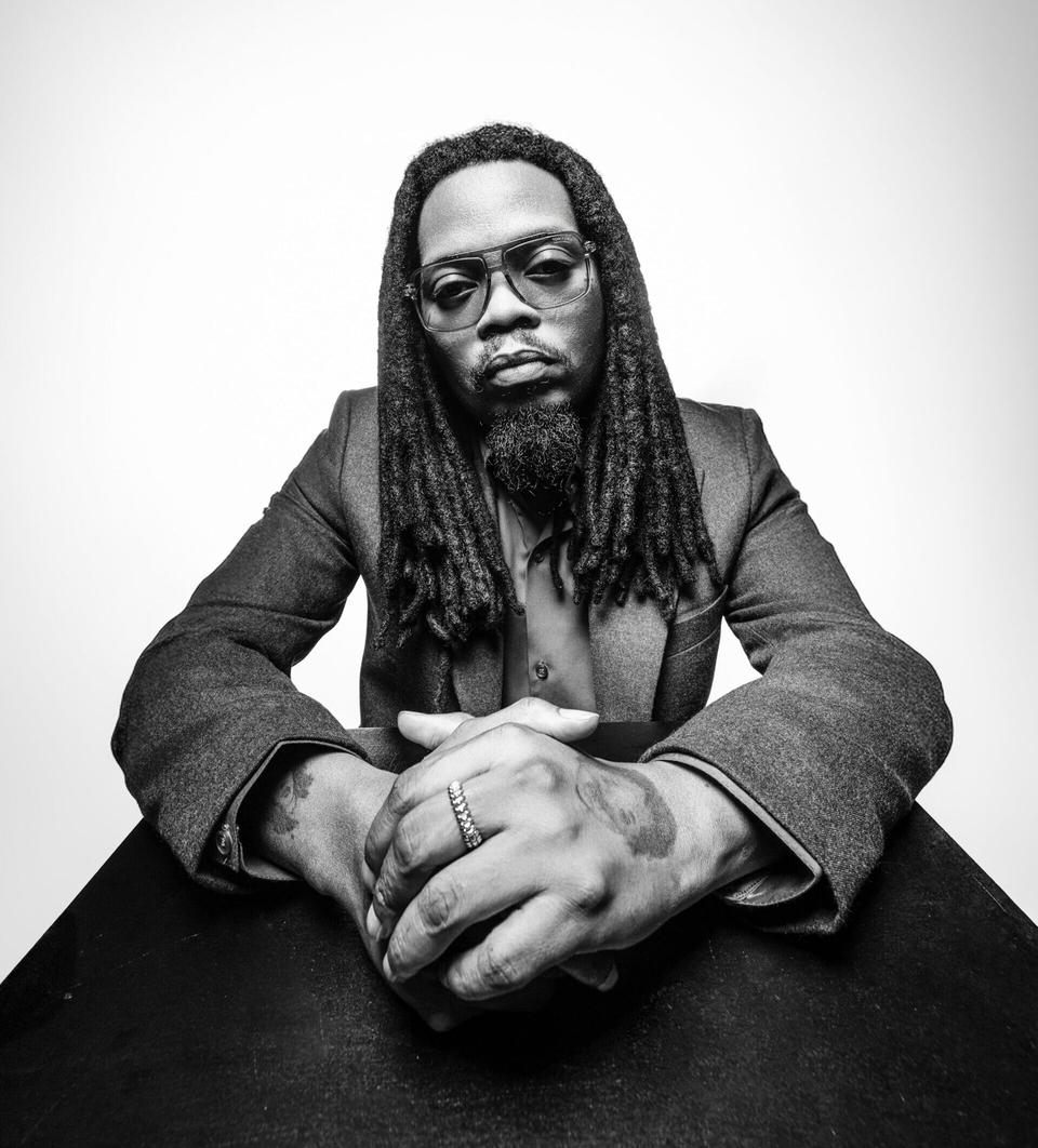 black and white portrait of a man with dreadlocks and glasses