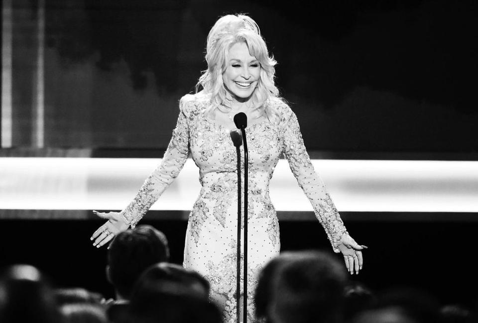 black and white photo of a woman in a sparkly dress speaking at a microphone