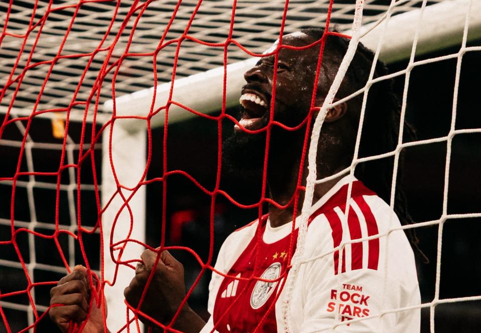 player celebrating with a shout behind the goal net, Ajax shirt with 'Team Rock Stars' sleeve text