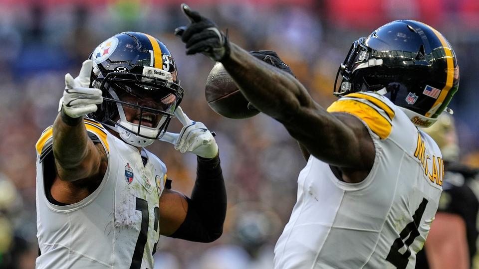 Two Steelers players in white kit celebrating, one holding the football and pointing upward