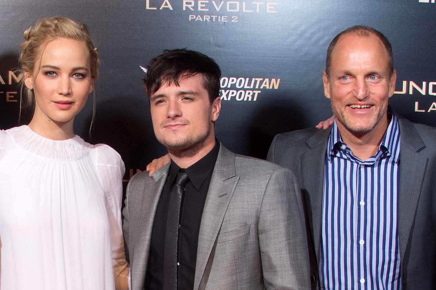 Jennifer Lawrence, Josh Hutcherson and Woody Harrelson posing at a Hunger Games premiere; backdrop titles are part of th