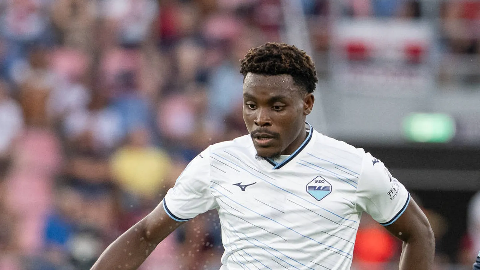 Fisayo Dele-Bashiru in Lazio's white kit, close-up action shot; kit maker and league patches only, no outlet watermark
