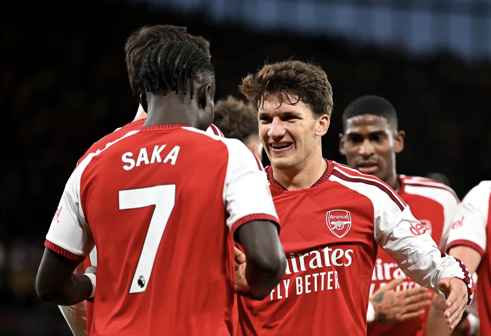 Arsenal's Saka (No 7, named on his shirt) celebrating with a team-mate in red