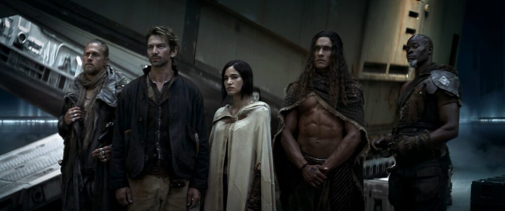 Five individuals standing in a spaceship